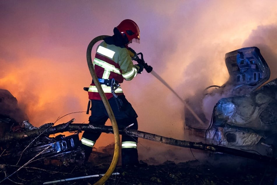 A Ukrainian rescuer works to extinguish a fire in a car following a missile attack in Sumy.