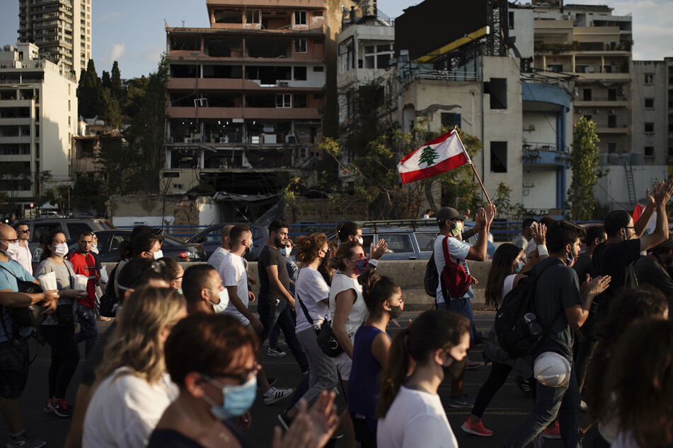 Beirut: Menschen gehen zu Ehren der Opfer der Explosion, die sich am 04.08.2020 im Hafen ereignete, durch eine Straße.