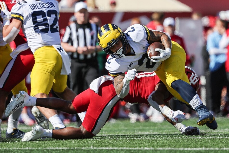 Blake Corum of the Michigan Wolverines runs the ball as Bryant Fitzgerald of the Indiana Hoosiers makes the tackle during the second half of Saturday's game at Memorial Stadium.