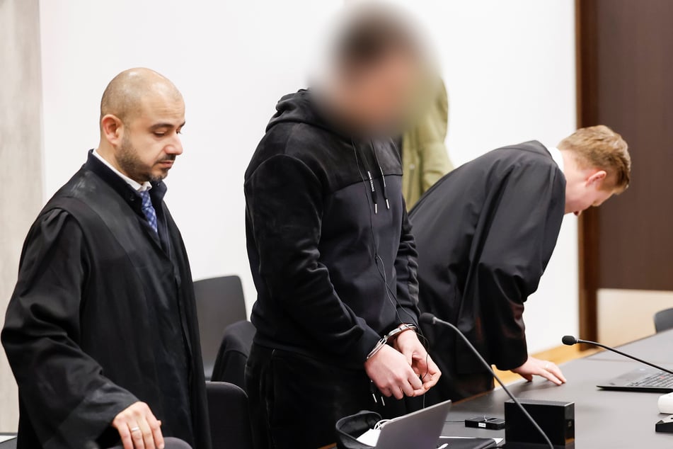 Der Angeklagte steht in Handschellen zwischen seinen Verteidigern Serkan Alkan (l.) und Florian Münch.