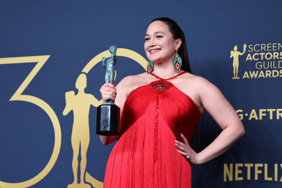 Lily Gladstone wears a stunning red gown as she poses with the award Female Actor in a Leading Role for Killers of the Flower Moon at the 30th Screen Actors Guild Awards.