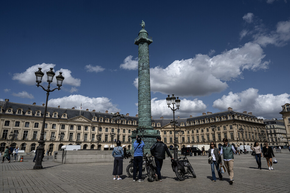 A picture taken in Paris on August 30, 2023 shows people walking and taking pictures at Place Vendome. Vogue is set to host a joint fashion show, dubbed Vogue World, on Paris' Place Vendome on Sunday.