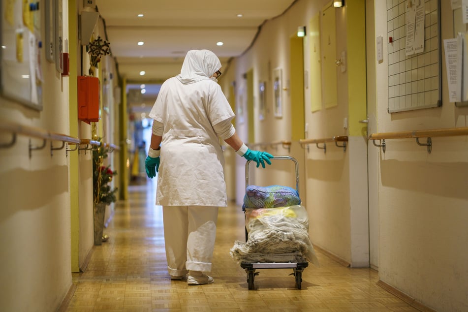 Eine Reinigungskraft zieht einen Wagen mit Wäsche einen der Gänge eines Alten- und Pflegeheimsheims entlang. Es gebe es nun "die Erwartung nach einer Normalisierung".