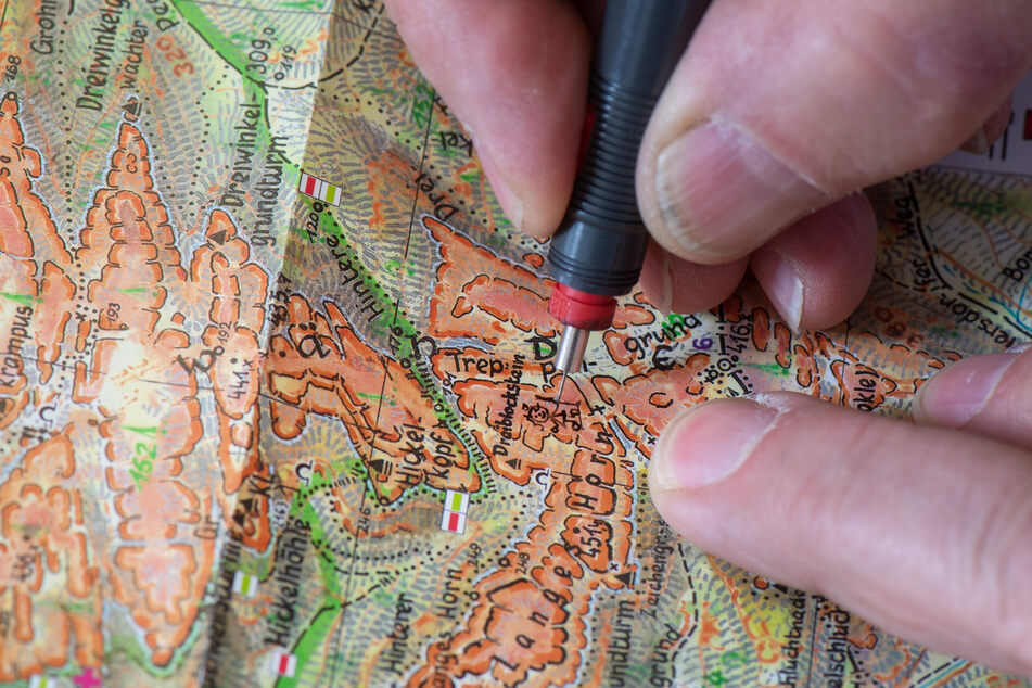 Mit Feder zeichnet der Kartograf sorgfältig alles auf seiner Karte ein.