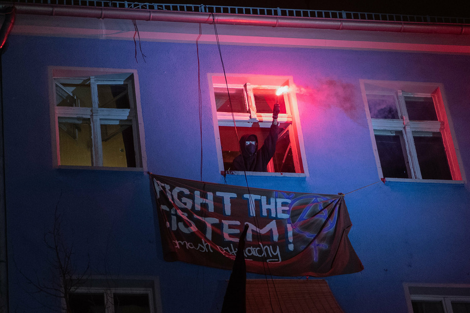 Ein Mann demonstriert mit einem Bengalo gegen die Räumung der Szene-Kneipe "Meuterei" in der Rigaer Straße.