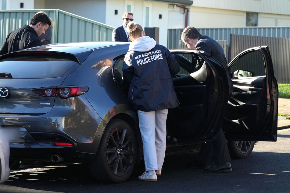 This handout photo from the New South Wales Police taken on Wednesday, shows Australian police in Sydney after arresting a man and charging him with allegedly stealing from a victim during last year's deadly mass shooting on Sydney's Bondi Beach.