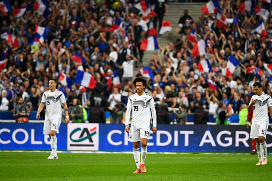Krasser Kontrast: Die deutschen Spieler um Mats Hummels (r.), Leroy Sané (M.) und Niklas Süle (l.) gucken betreten in die Gegend, während die französischen Fans ein Tor ihrer Mannschaft bejubeln.