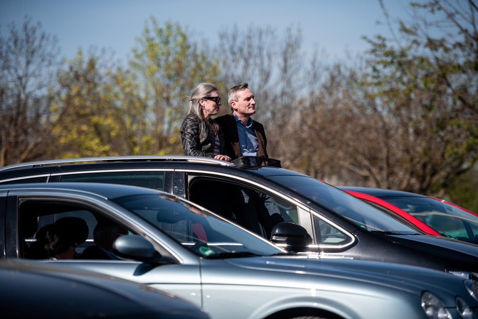 Oberbürgermeister Thomas Geisel sitzt mit seiner Frau Vera in seinem Auto und guckt aus dem Dachfenster Richtung Bühne.