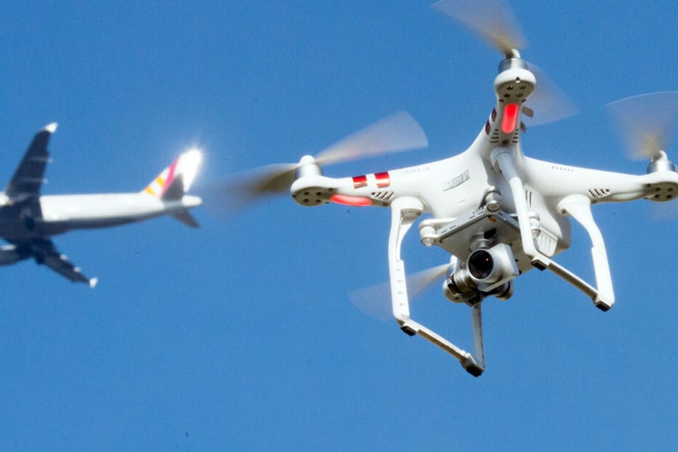 Eine Drohne fliegt in der Nähe eines Flugzeugs. (Symbolbild)