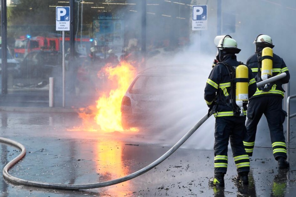 Einsatzkräfte löschen das brennende Fahrzeug.