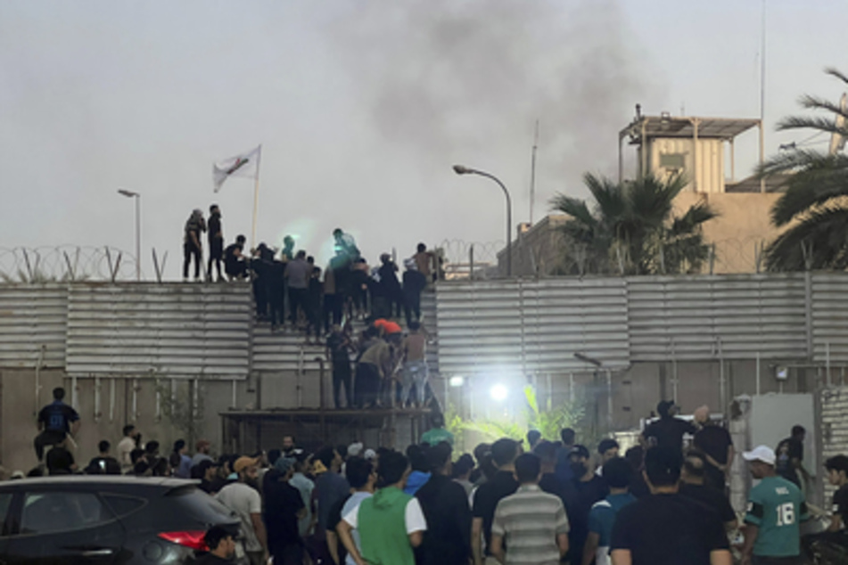 Demonstranten klettern über die Mauer der schwedischen Botschaft in Bagdad.