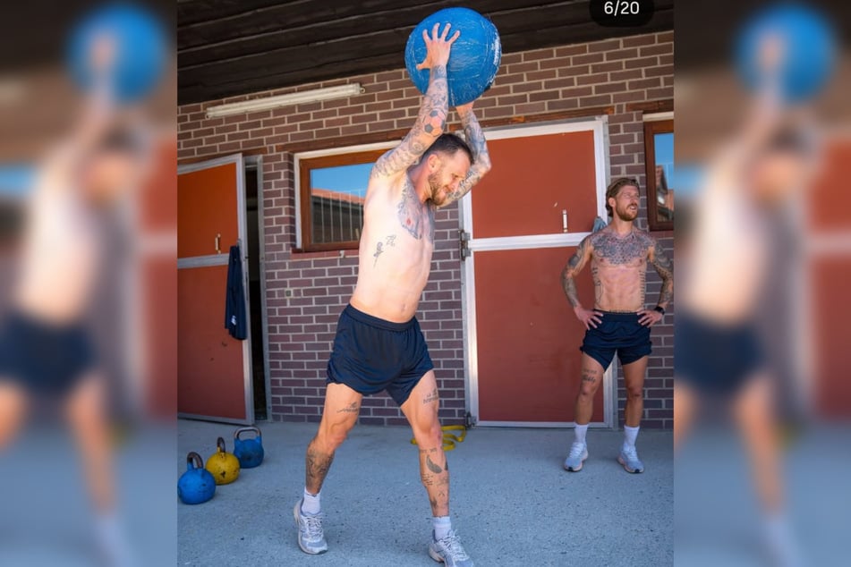 Tim Rieder (32, l.) stemmt einen Ball über den Kopf, Philip Türpitz (34, r.) schaut zu. Am Rand liegen die schweren Kettlebells.