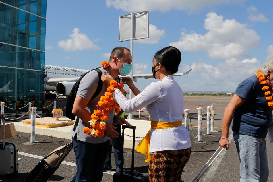 Ein Flughafenbeamter (M) begrüßt einen Passagier bei seiner Ankunft am Flughafen Bali.