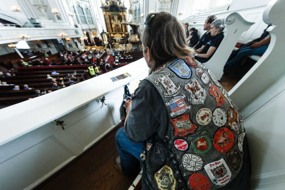 Ein Motorradfahrer in seiner mit Patches benähten Kutte sitzt beim Motorradgottesdienst MoGo in der Hauptkirche St. Michaelis.