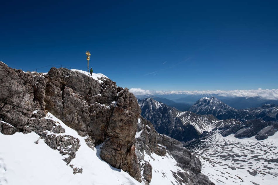 Bayern, Garmisch-Partenkirchen: Ein Bergsteiger nutzt das schöne Wetter, um zum Gipfelkreuz auf der Zugspitze zu klettern.