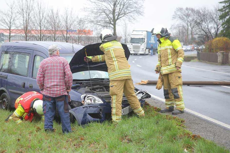 Kameraden der Feuerwehr stehen an dem Unfallauto und prüfen, ob Betriebsstoffe auslaufen.