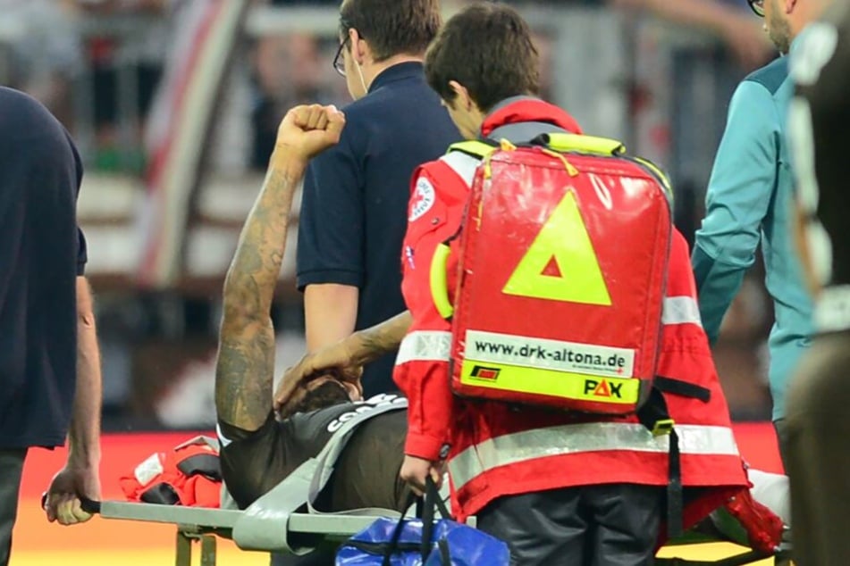 Der schwer Verletzte erhebt eine Faust, als der Gesang der Fans ertönt.