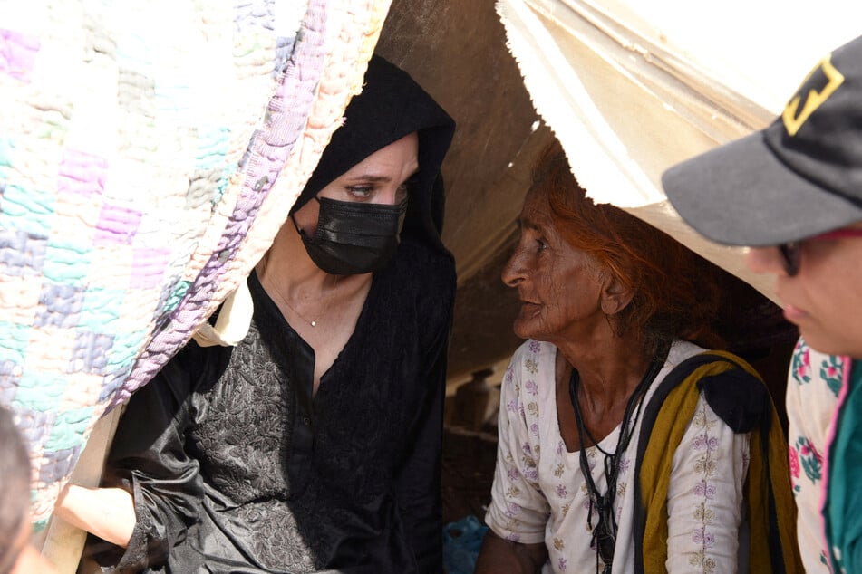 Jolie listens to a woman who was displaced by the floods.
