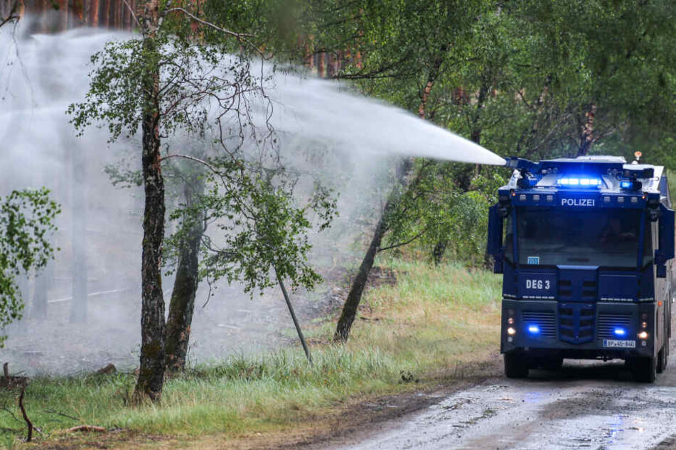 Ein Wasserwerfer der Polizei löscht einzelne Glutnester im Wald bei Lübtheen.