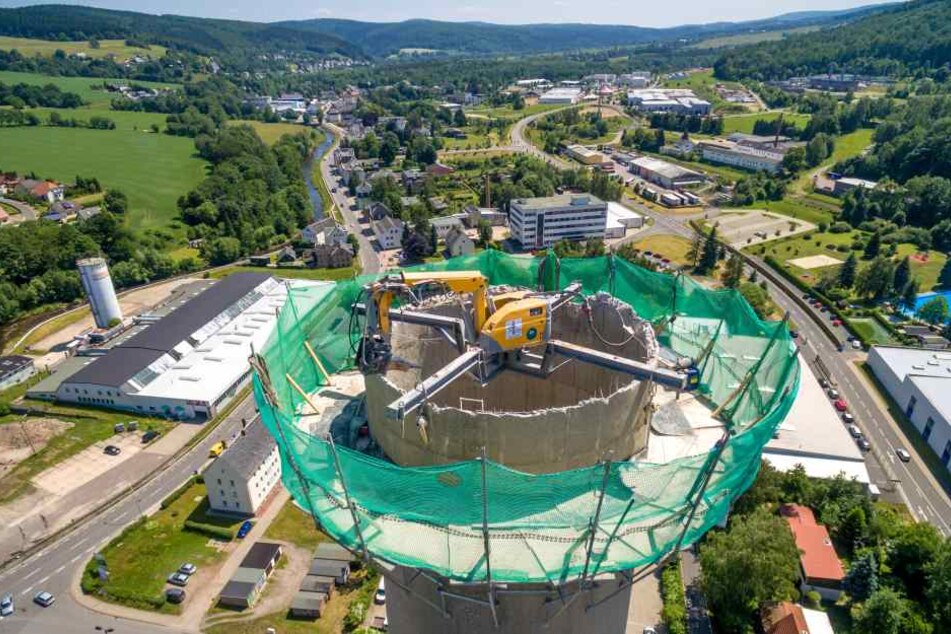 Der Mitte der 1980er Jahre errichtete Schornstein des ehemaligen Heizkraftwerkes in Olbernhau wird derzeit abgerissen. Eine Baggerspinne knabbert sich von oben nach unten.