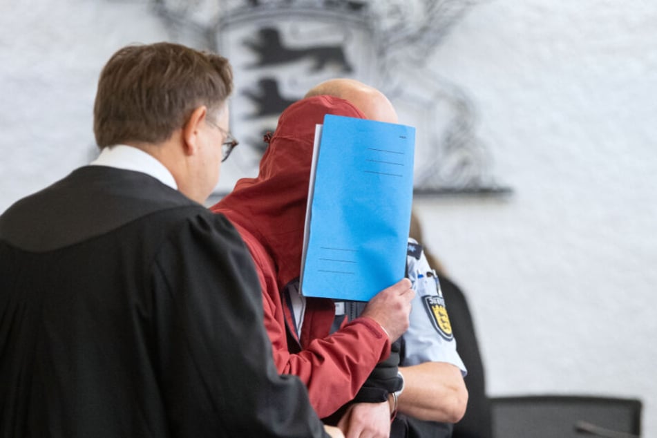 Der Angeklagte (M) in einem Mordprozess nach einem tödlichem Unfall wird von einem Justizbeamten in einen Gerichtssaal des Landgerichts Stuttgart geführt.