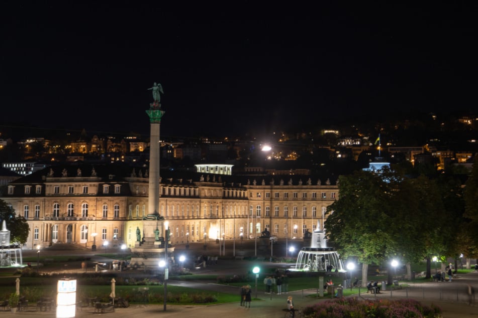 Menschen gehen am Samstagabend über den Schlossplatz. Die Stadt Stuttgart überschreitet die Warnstufe.