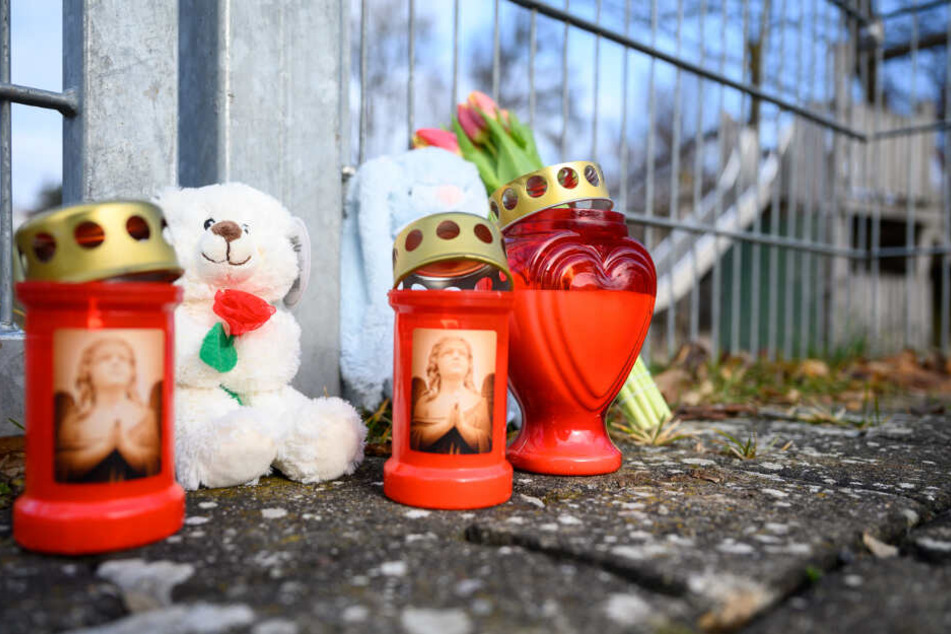 Kerzen, Blumen und Kuscheltiere stehen vor dem Eingang zum Spielplatzgelände.
