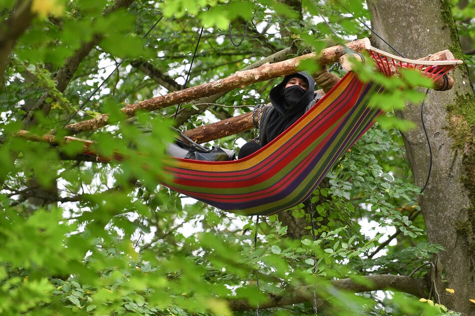 Eine Aktivistin hängt im Maulbacher Wald in einer Hängematte in einem Baum.