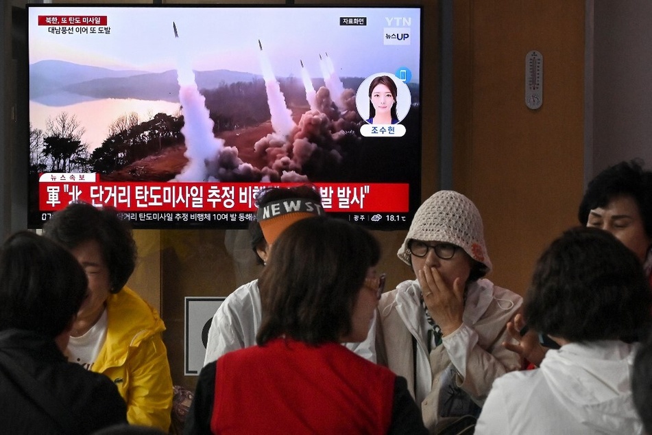 People a train station in Seoul sit in front of a television screen showing a news broadcast on a North Korean missile test.