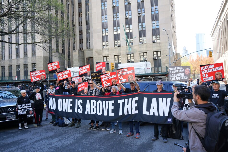 Anti-Donald Trump protesters hold a sign that reads, "No one is above the law," while calling for the former president to finally be held accountable for his alleged crimes.