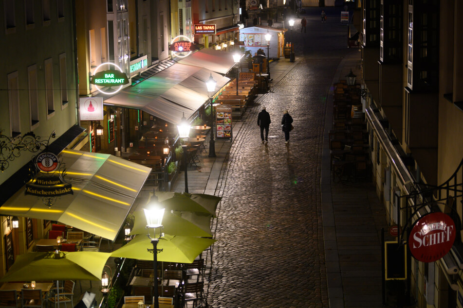 Passanten laufen am Abend durch die Münzgasse an leeren Restaurants und Bars vorbei.