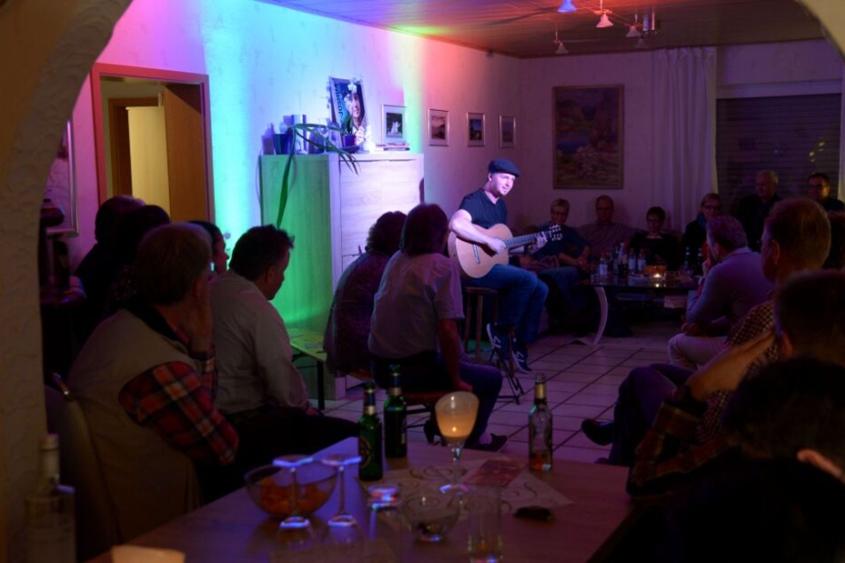Der Musiker Joshua Carson tritt in einem fremden Wohnzimmer auf.
