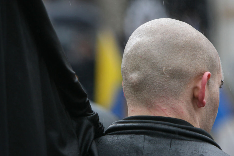 Ein Teilnehmer der Neonazi-Demonstration steht mit seiner Fahne während einer Kundgebung im Regen (Symbolbild).