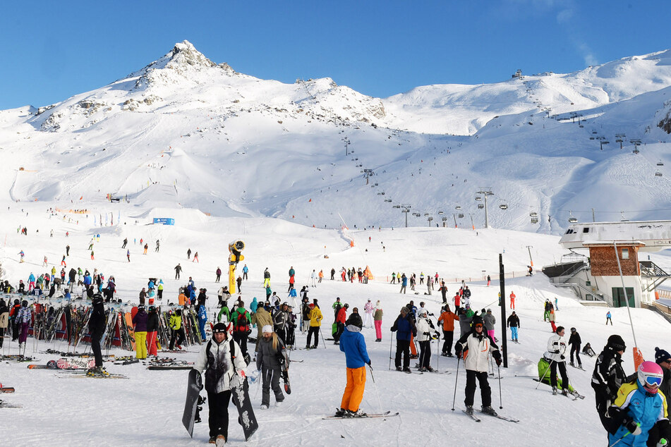 Wintersportler stehen an einer Skipiste.