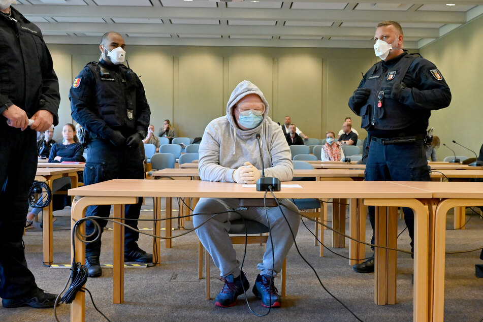 Mit Schutzbrille und Mundschutz sitzt der 47-jährige Angeklagte beim Auftakt des Verfahrens im Gerichtssaal.