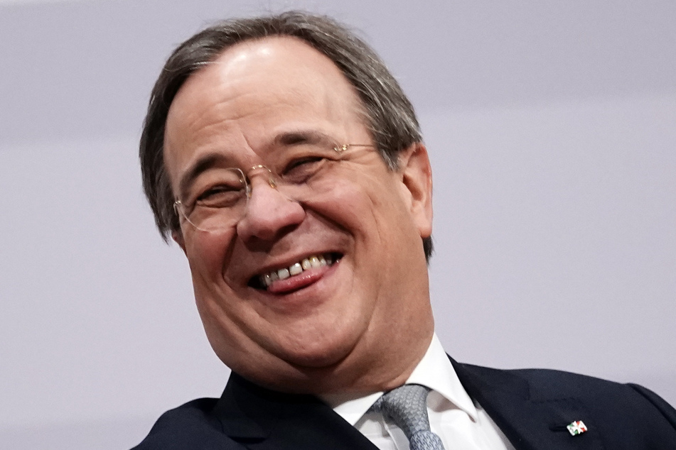 Der neue Parteivorsitzende Armin Laschet (59) sitzt beim digitalen Bundesparteitag der CDU auf dem Podium und lacht.