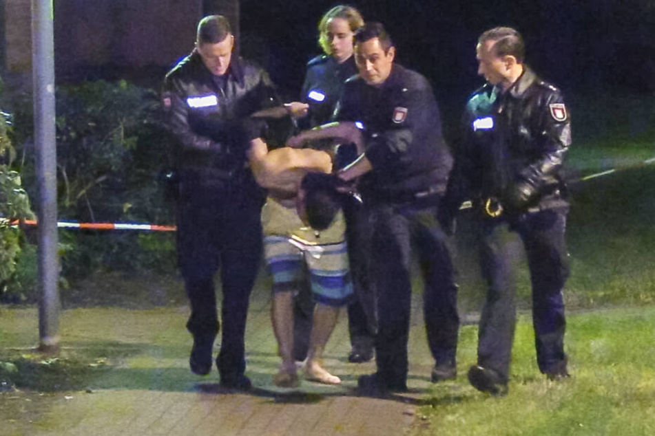 Polizisten führen einen jungen Mann in Badehose ab.