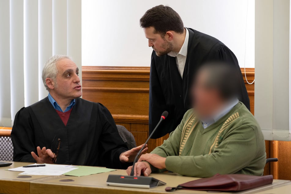 Der Angeklagte (r.) unterhält sich vor dem Beginn der Verhandlung mit seinen beiden Rechtsanwälten.