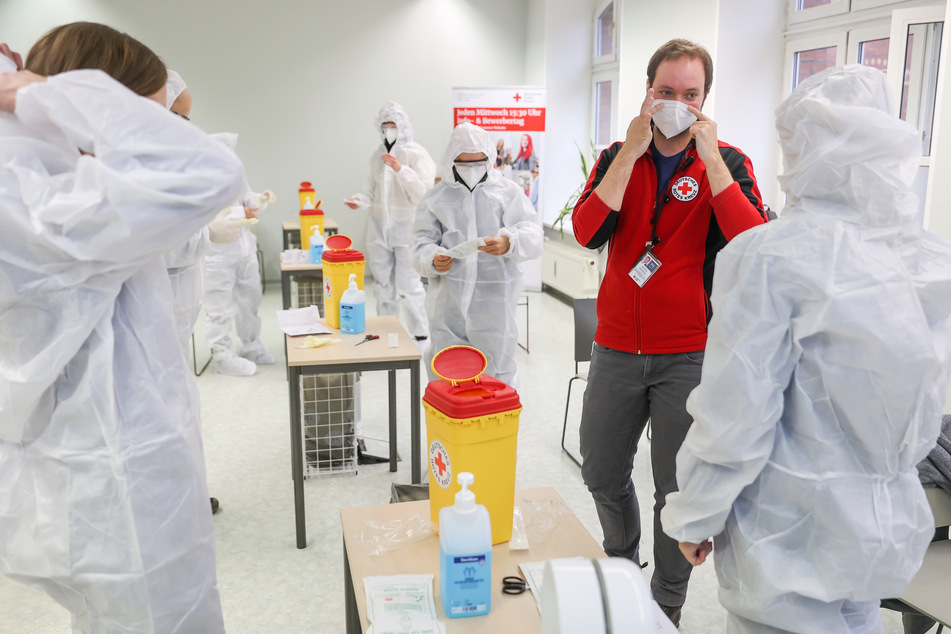 Dozent Jascha Gionkar (2.v.r.) erläutert den Teilnehmer eines Kurses für das Anwenden von Antigen-Schnelltest auf SARS-VoV-2 das Anlegen der Schutzausrüstung. Das Deutsche Rote Kreuz bildet nun Corona-Schnelltester aus.