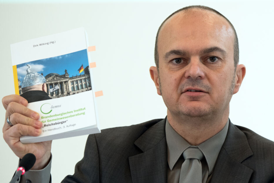 Der Leiter des Brandenburger Verfassungsschutzes, Frank Nürnberger, zeigt während einer Pressekonferenz ein Handbuch zum Umgang mit den sogenannten Reichsbürgern.