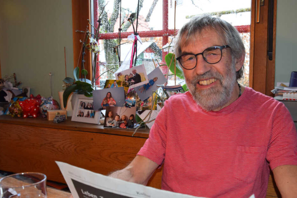 Eberhard Lieb liest Zeitung, im Hintergrund Familienbilder.