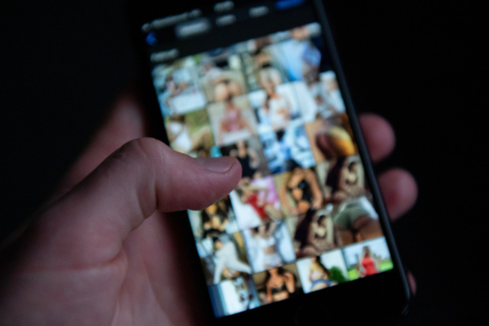 Ein Mann schaut sich auf einem Smartphone pornografische Bilder an. Wegen der Verbreitung von Kinderpornografie sitzt ein Schwabe nun in Untersuchungshaft. (Symbolbild)