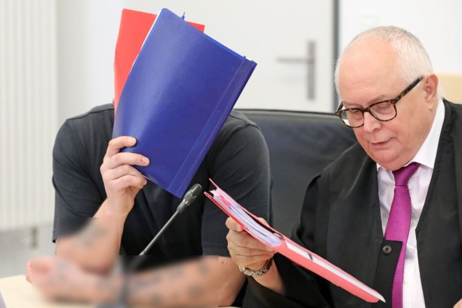 Einer der beiden Angeklagten (l) unterhält sich mit seinem Verteidiger Edgar Breitsprecher im Saal des Landgerichts.