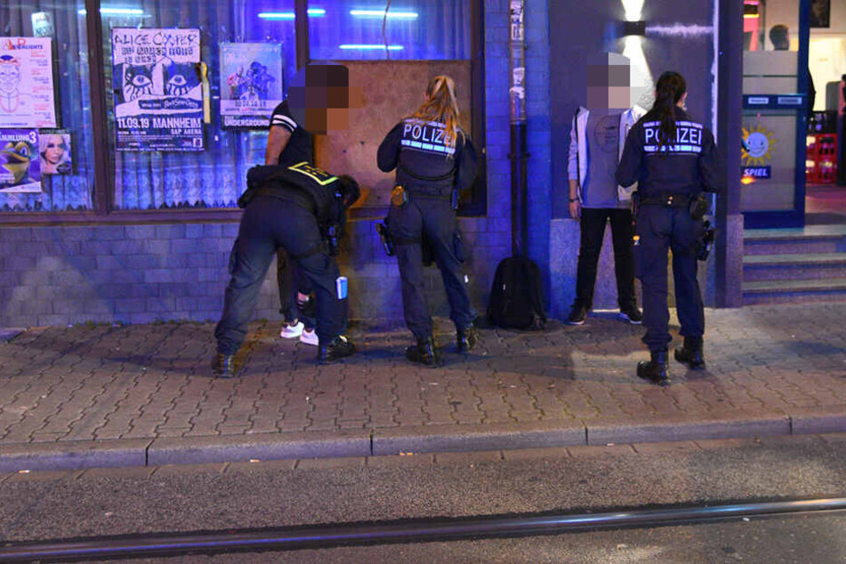Zwei Männer werden von den Polizisten gefilzt.