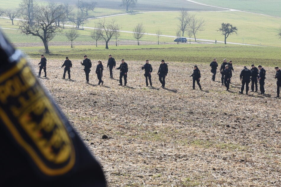 Einsatzkräfte der Polizei suchen nach dem Leichenfund ein Gebiet ab.