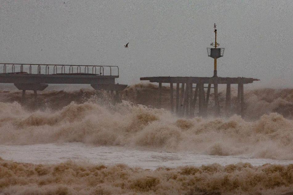 Wellen treffen eine teilweise beschädigte Brücke während eines Sturms am Strand von Badalona.