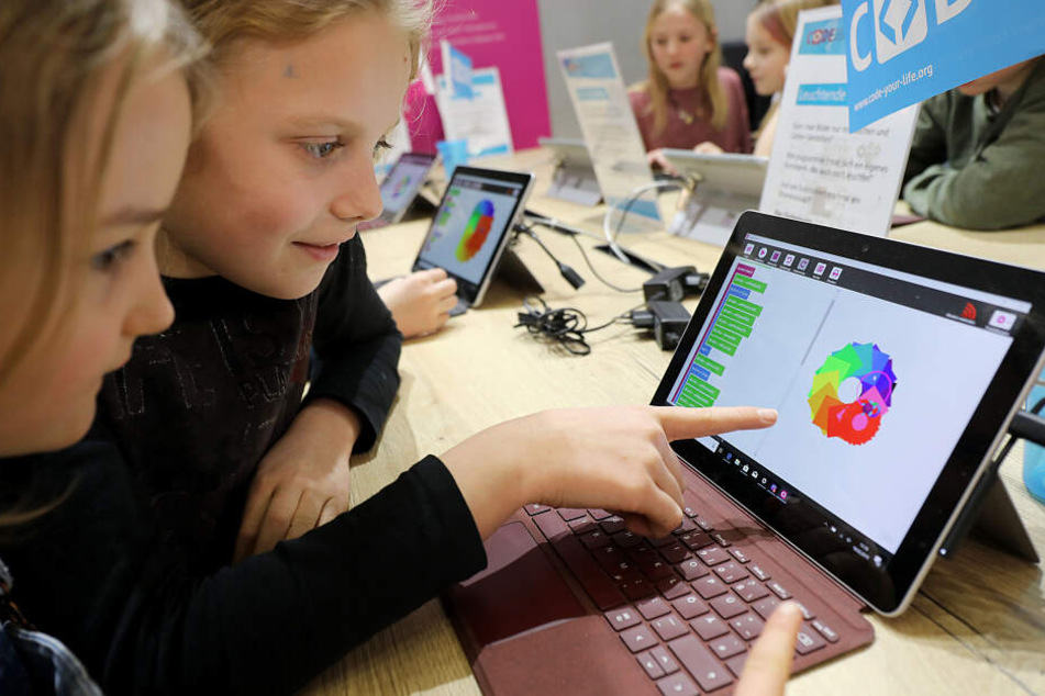 Kinder betrachten auf der Didacta in Köln einen Laptop.