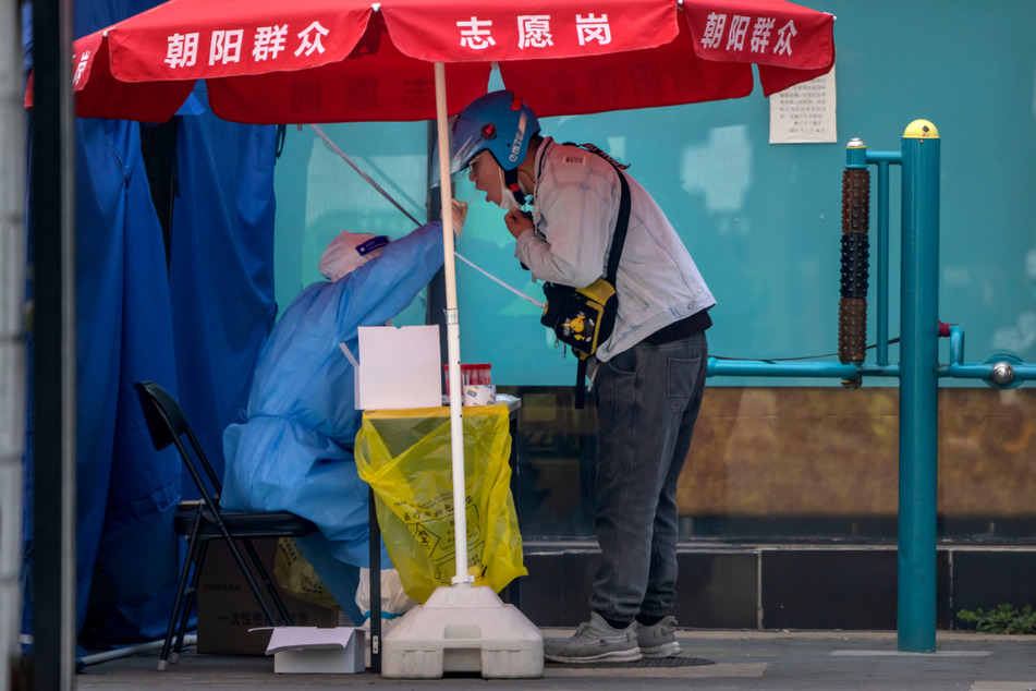 Ein Gesundheitsmitarbeiter nimmt in einem Coronavirus-Testzentrum in Peking den Rachenabstrich eines Lieferfahrers für einen Coronavirus-Test.