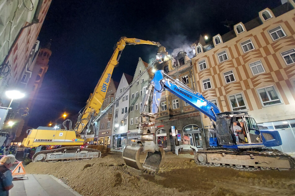 Bagger stehen vor dem denkmalgeschützten Haus in Augsburg, aus dem es noch qualmt. Das Feuer hat das historische Gebäude schwer beschädigt, es musste weitestgehend abgetragen werden.