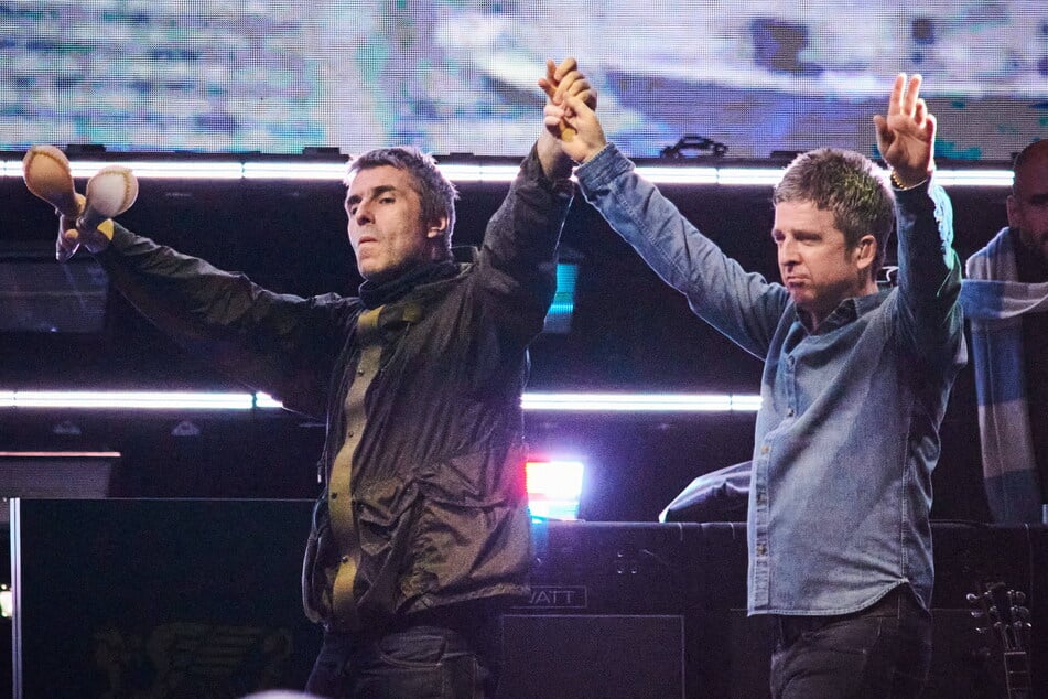 Liam Gallagher (l.) and Noel Gallagher of Oasis walk onstage together during their reunion tour in Toronto, Canada, on August 24, 2025.